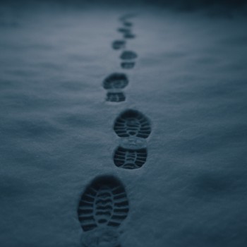 Boot steps leaving a narrow trail across soft winter snow