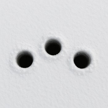 Three drilled ice holes forming a soft arc on packed snow