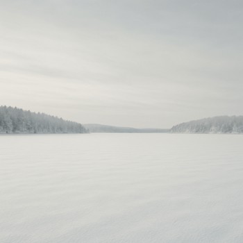 Wide frozen lake basin covered in soft snow under pale winter light